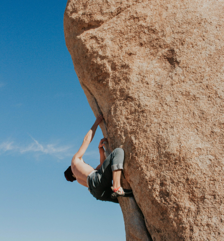 a shirtless man climbing a boulder outdoor